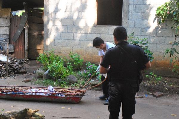 Investigador traslada el cadáver de Romeo Fidel Gutiérrez, quien fue encontrado en Nuevo San Carlos. (Foto Prensa Libre: Jorge Tizol)