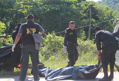 Peritos del Ministerio Publico y agentes de la Policía recogen evidencias en el lugar del hallazgo en La Libertad. (Foto Prensa Libre: Rigoberto Escobar)