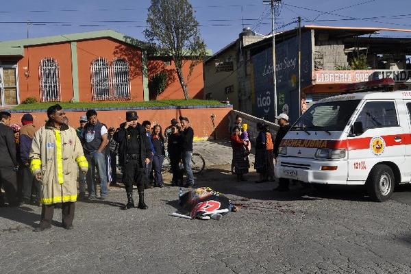 Policías y bomberos observan cadáver.