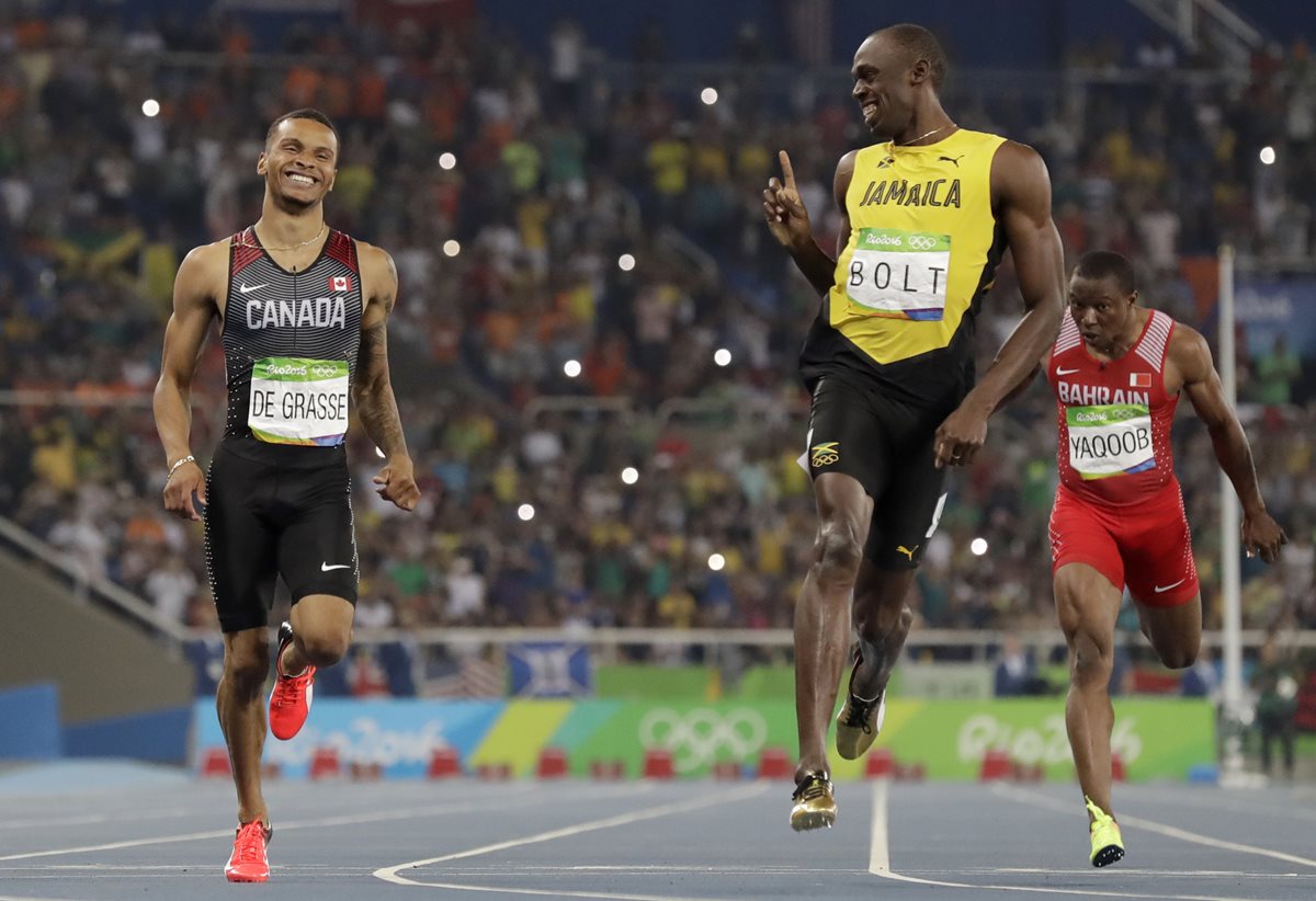 Usain Bolt le sonríe al canadiense Andre de Grasse luego de que intentará ganarle el heat de los 200 metros. (Foto Prensa Libre: AP)