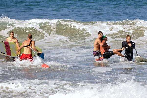 Dos hombres ayudan en el rescate del hombre herido por el tiburón en California (Foto Prensa Libre: AP).