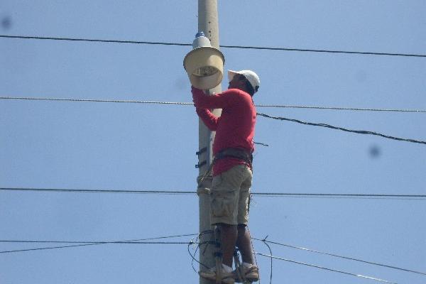 Integrante de un grupo de vecinos   repara una  lámpara, en Taxisco.