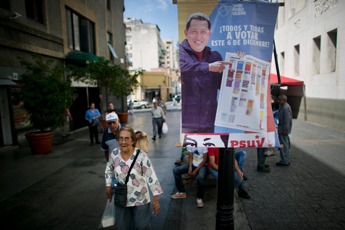 Peatones caminan por las calles de Caracas en medio de propaganda que muestra al presidente Hugo Chávez llamando al voto en favor del oficialismo. (Foto Prensa Libre: AP).