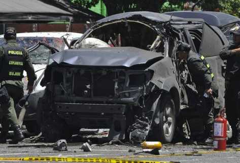 Policías observan los restos del auto de Fernando Londoño, ex ministro del Interior del gobierno de Álvaro Uribe. (Foto Prensa Libre: AFP)