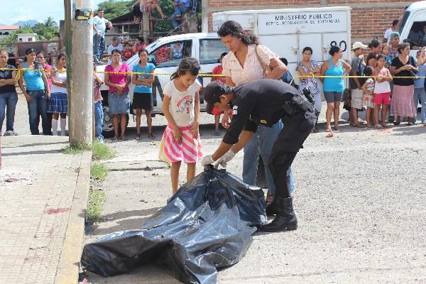 Un agente de la Policía muestra a familiares el cadáver del piloto  de microbús, en Jutiapa.