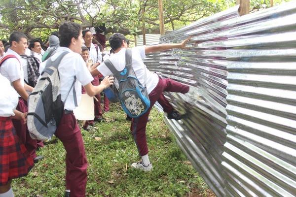 Estudiantes destruyen cerco de lámina que colocaron trabajadores de constructora en instituto. (Foto Prensa Libre: Óscar González)