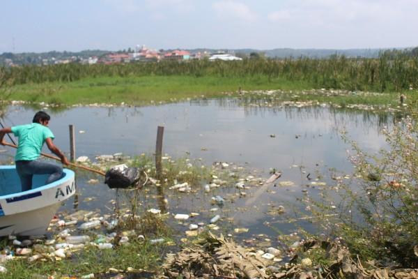 Un empleado municipal recoge una bolsa con desechos en el arroyo Pijul, en San Benito, Petén.