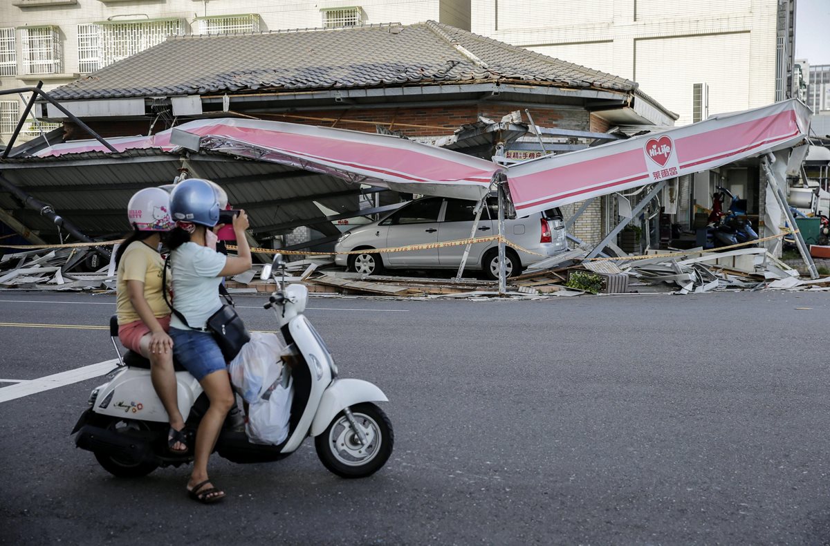 Una motorista fotografía una tienda destrozada tras el paso del supertifón Meranti en Kaohsiung, Taiwán. (Foto Prensa Libre: EFE).