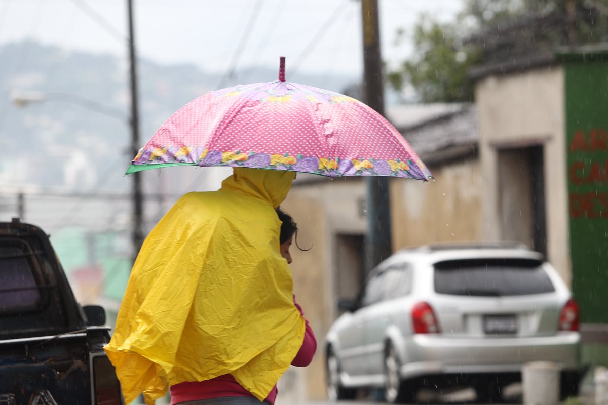 Una madre carga a su hijo para cubrirlo de la lluvia que cae en la zona 1 capitalina. (Foto Prensa Libre: Erick Ávila)