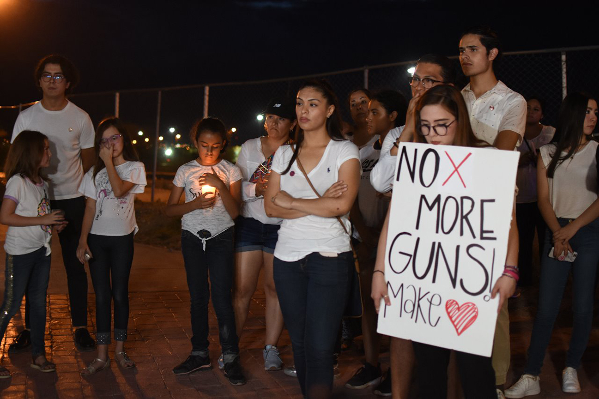 Personas manifiestan este sábado en la línea fronteriza de Ciudad Juárez, México, luego del tiroteo en un centro comercial de El Paso. (Foto Prensa Libre: EFE).