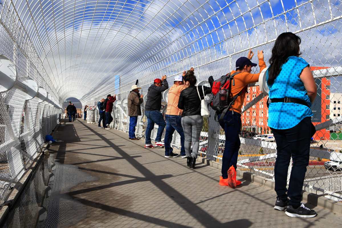 CIUDAD JUÁREZ (MÉXICO),21/11/2019.- Migrantes observan este jueves hacia el consulado de Estados Unidos en la fronteriza Ciudad Juárez, en el estado de Chihuahua (México). Según testigos, el hallazgo de una maleta negra abandonada a las afueras de una tienda contigua al edificio fue lo que detonó la alerta para que el consulado evacuara a su personal. En el sitio trabajan personal de Seguridad Pública Municipal y Bomberos para resguardar la zona, mientras agentes de Operativos Especiales realizan el protocolo que corresponde a estos casos. EFE/ Luis Torres