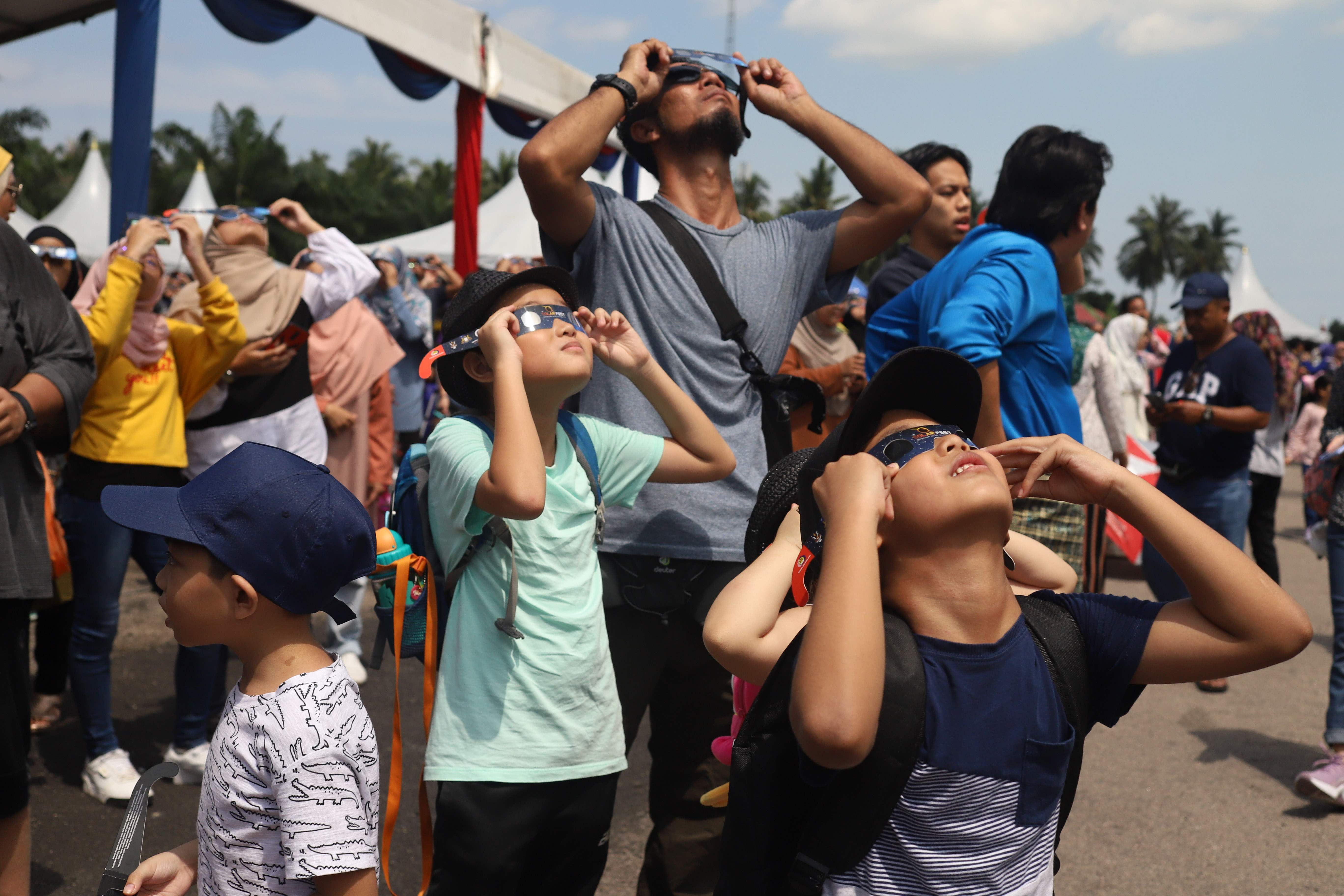 Con protección solar, varios observadores en Malasia disfrutan del eclipse anular. (Foto Prensa Libre: AFP)