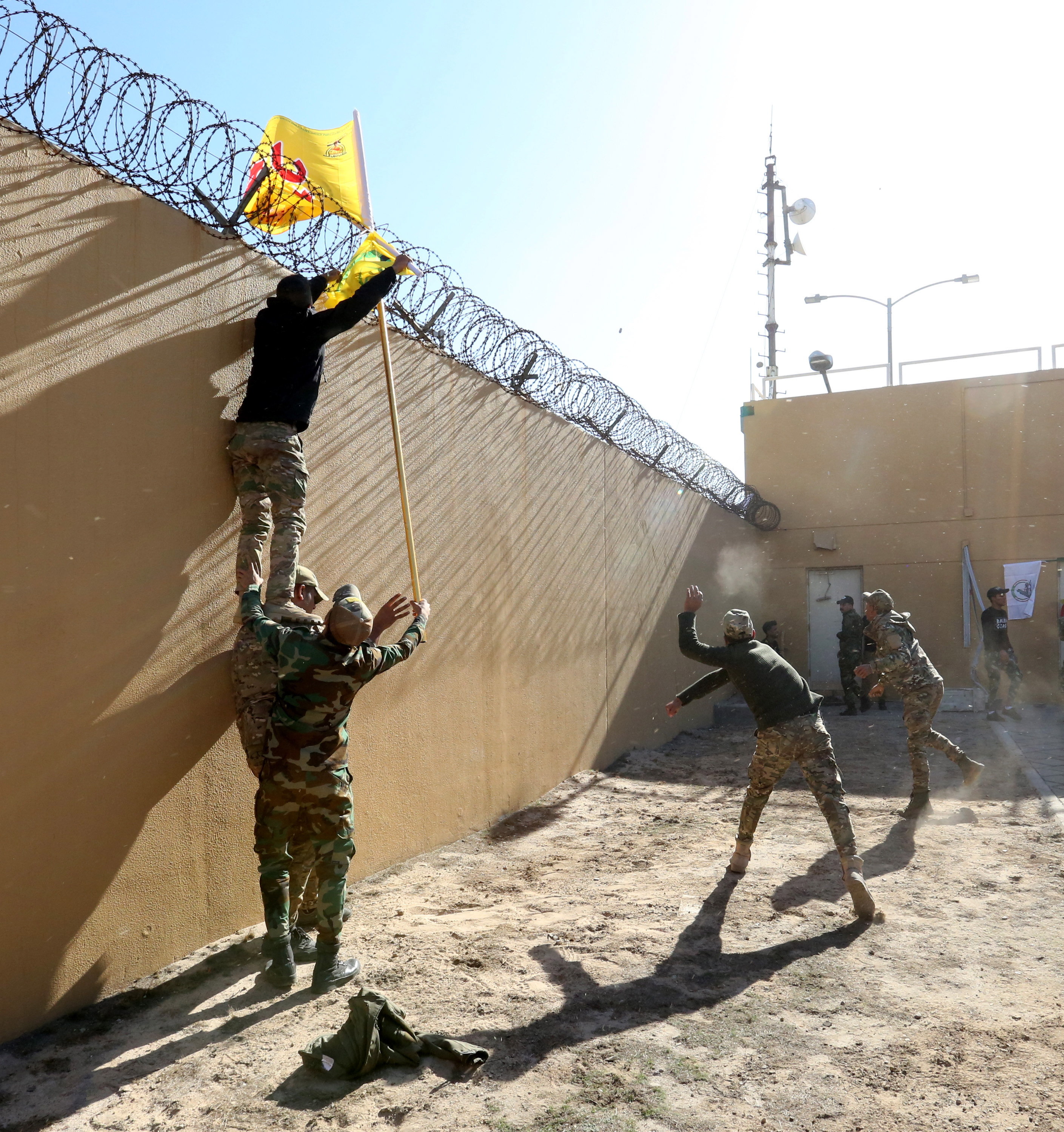 Baghdad (Iraq), 31/12/2019.- Members of Iraqi Shiite 'Popular Mobilization Forces' armed group and their supporters throw stones as they attack the US Embassy during a protest in Baghdad, Iraq, 31 December 2019. According to media reports, the US ambassador and other members of the staff were evacuated as dozens of people broke into the embassy's compound after setting fire to the reception area. The attack at the embassy follows a deadly US airstrike that killed 25 fighters of the Iran-backed militia on 29 December. (Atentado, Protestas, Incendio, Estados Unidos, Bagdad) EFE/EPA/AHMED JALIL