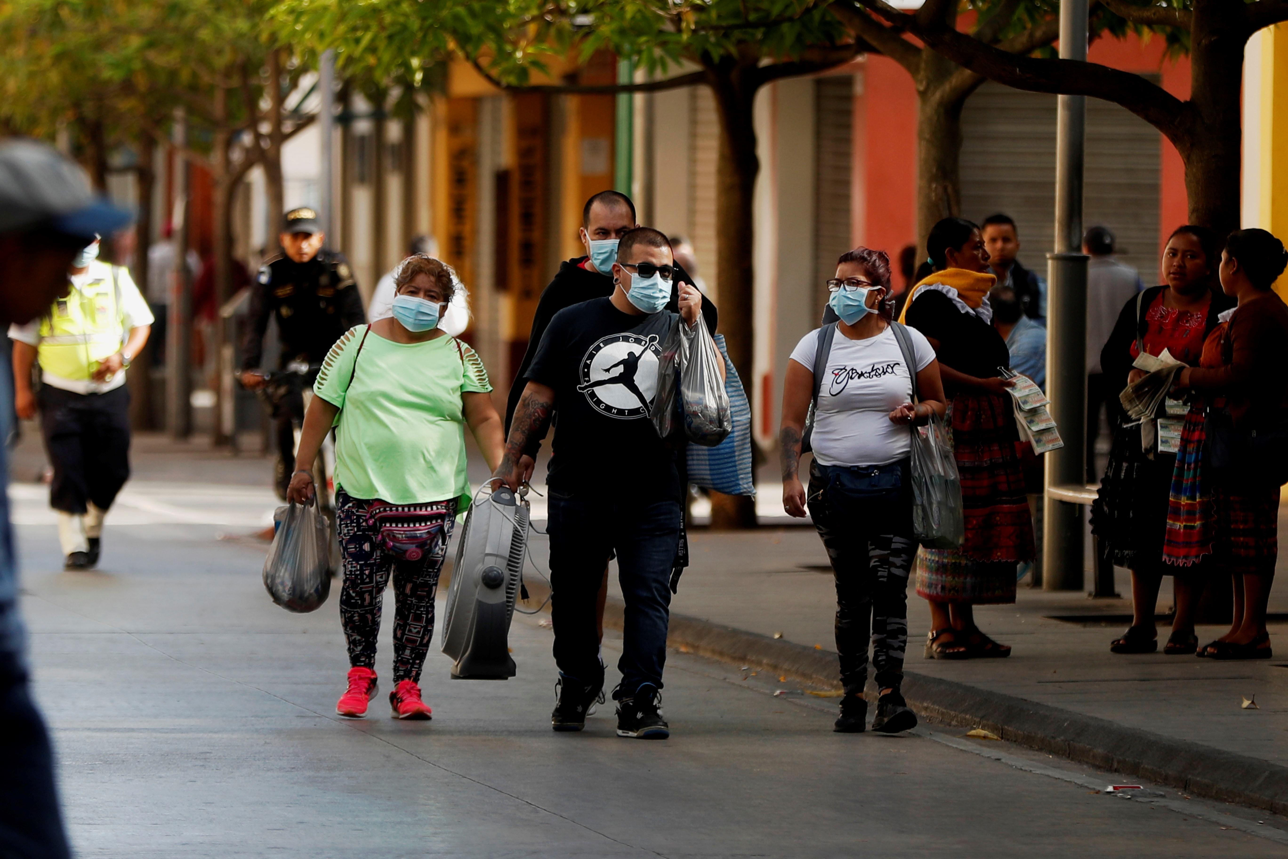 Guatemaltecos siguen en las calles y algunos optan por cubrirse la boca y nariz con mascarillas. (Foto Prensa Libre: EFE)