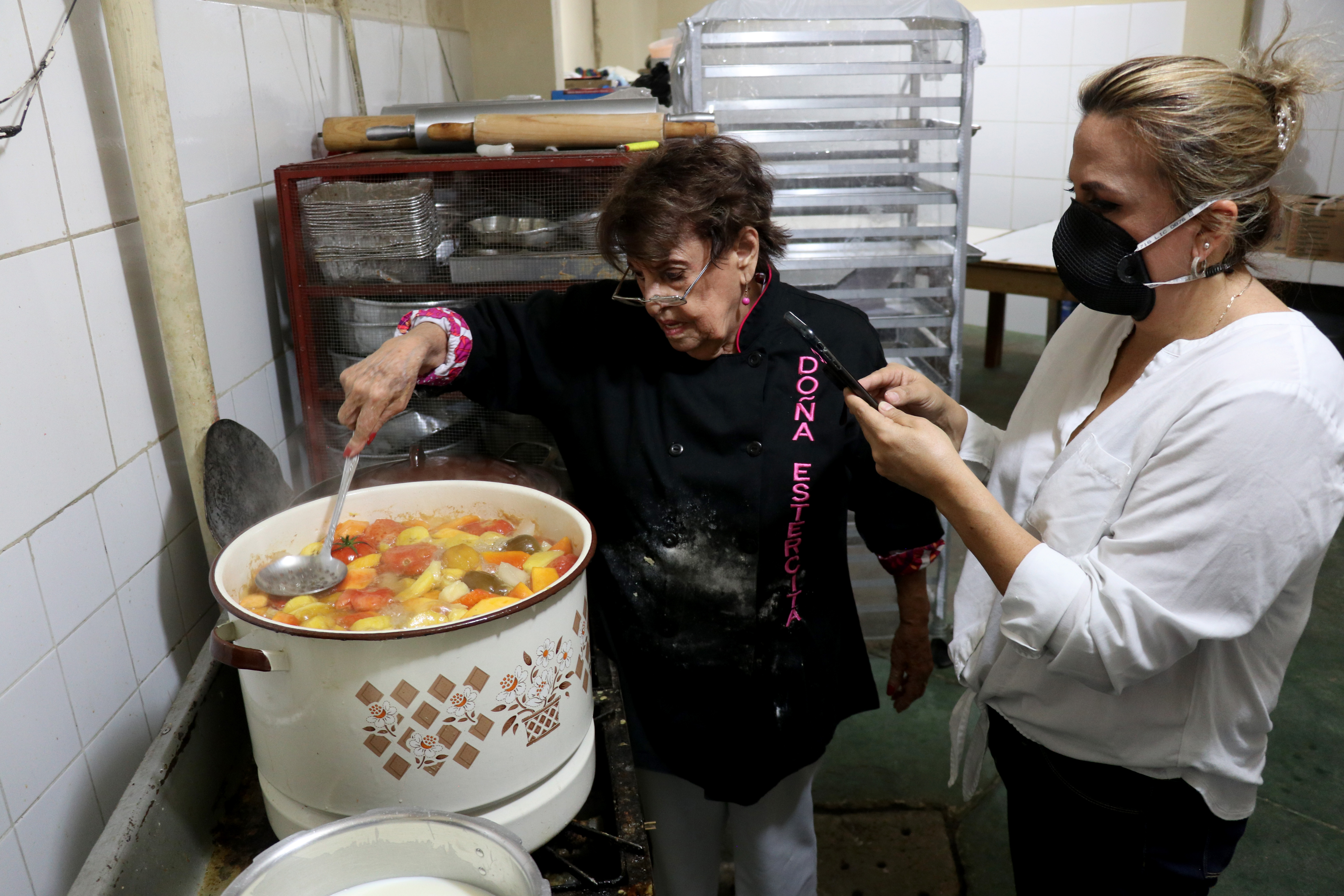 Doña Olga muestra como cocinar la Miel de Semana Santa, mientras su hija María Olga hace la transmisión en redes sociales. (Foto Prensa Libre: Mike Castillo)