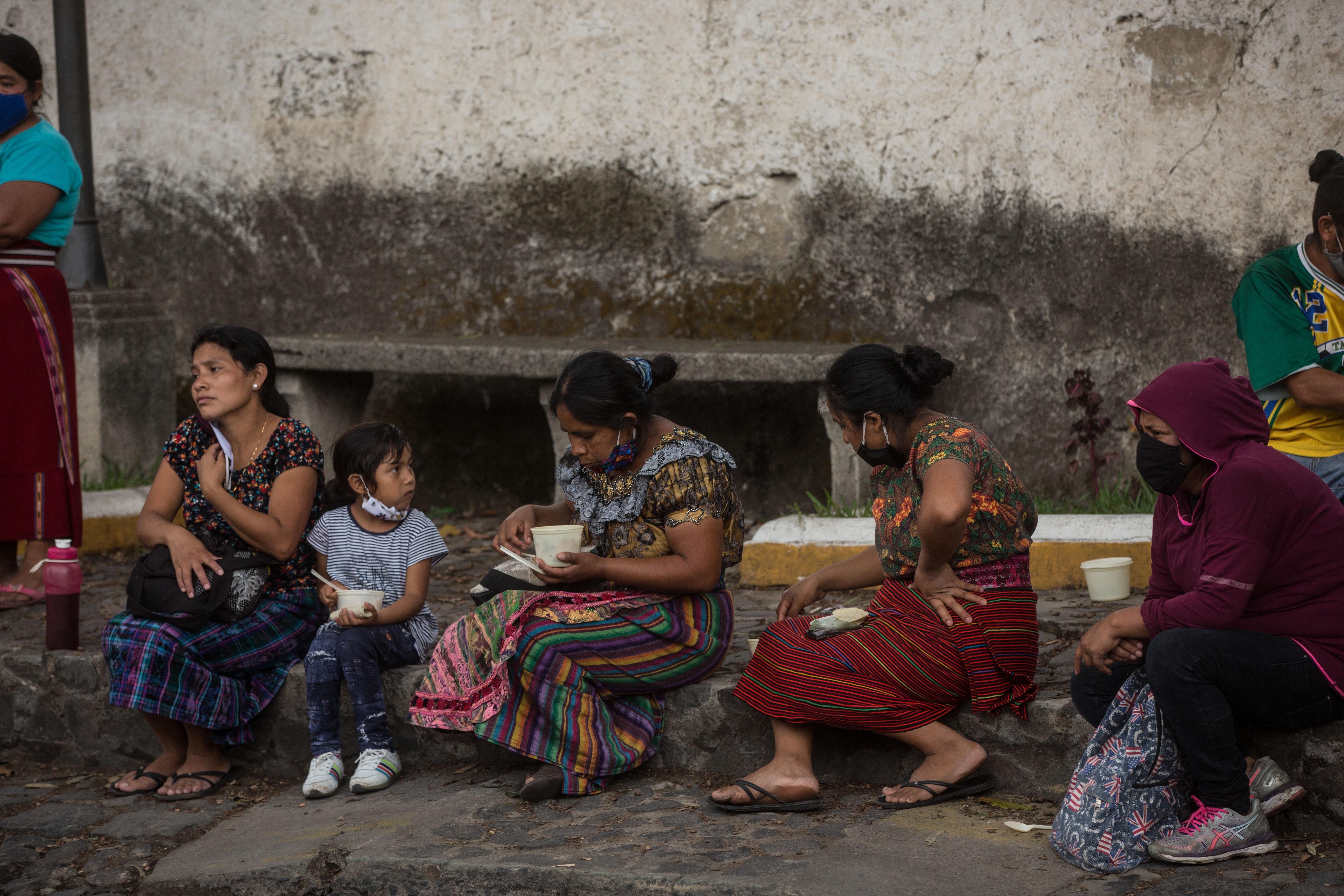 Fotografía del 29 de mayo de 2020 que muestra unas personas después de recibir almuerzos gratuitos de la organización Banderas Blancas Sacatepéquez, en el centro cultural Casa del Río en Antigua (Guatemala. (Foto Prensa Libre: EFE)