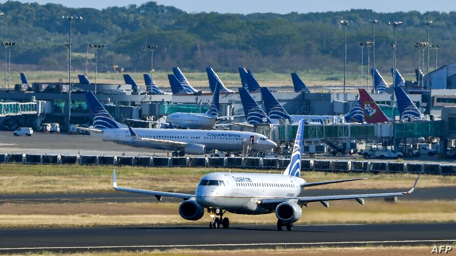Un avión de Copa Airlines es visto en una pista mientras otro aterriza del aeropuerto internacional de Tocumen, el 22 de marzo de 2020.  (Foto Prensa Libre: AFP)