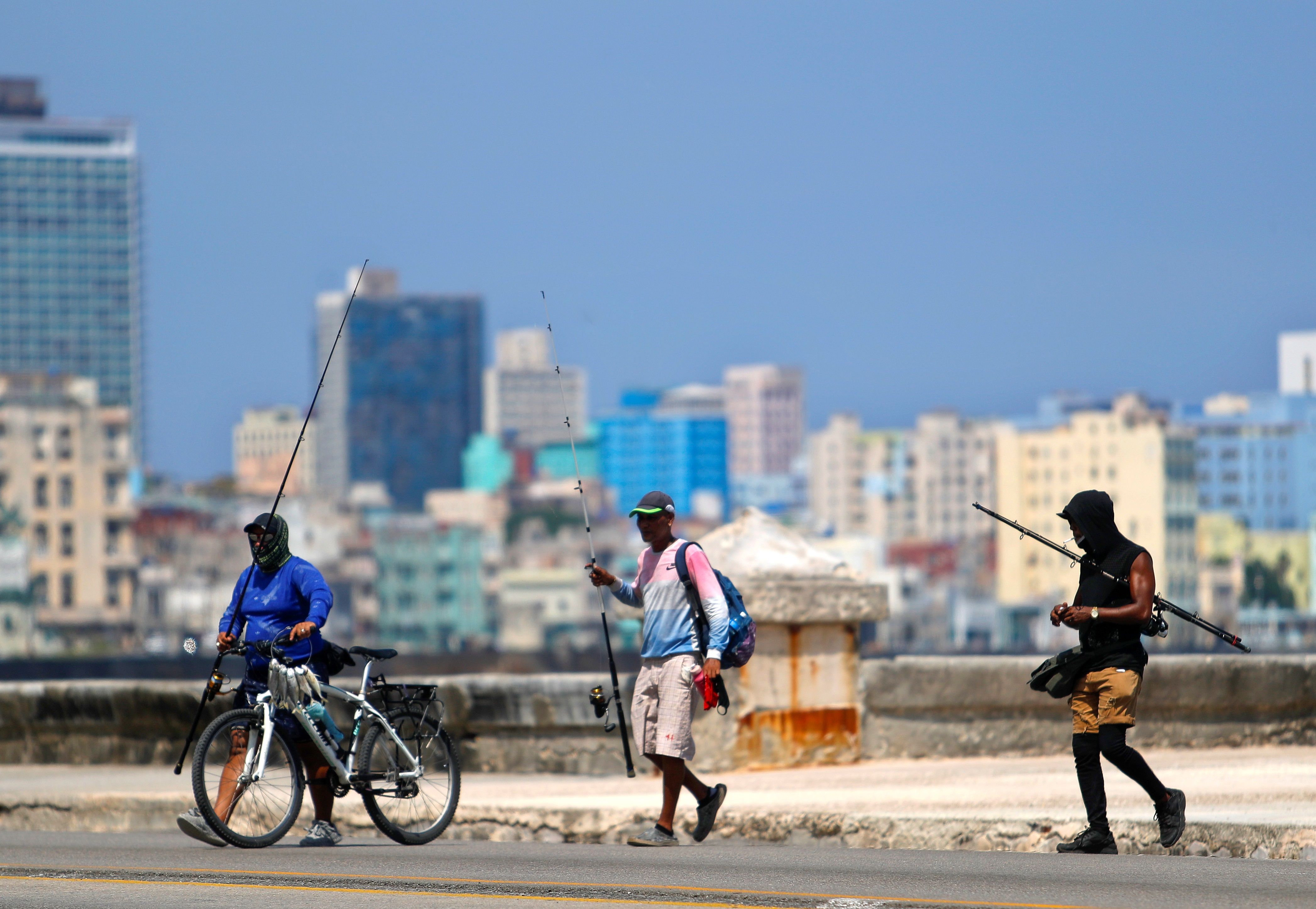 -FOTODELDIA- AME6226. LA HABANA (CUBA), 04/08/2020.- Tres pescadores caminan por el malecón este martes, en La Habana (Cuba). Cuba sumó este martes 31 nuevos casos de COVID-19, de los cuales 10 son importados, y registró la primera muerte por el virus en más de tres semanas, según el Ministerio de Salud Pública (Minsap) de la isla, donde se mantiene el repunte en los contagios diarios. EFE/ Yander Zamora