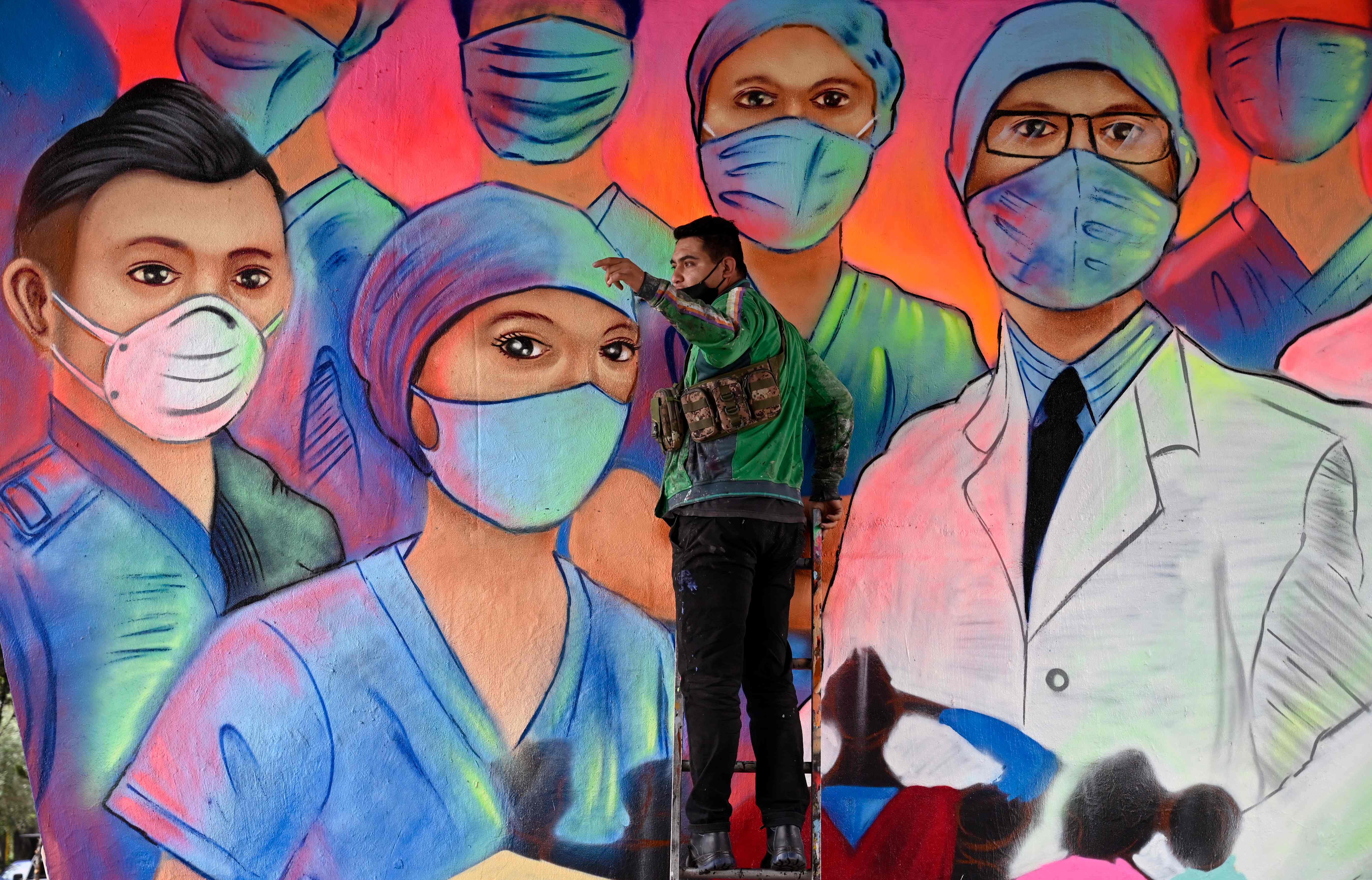 El artista urbano Sergio Morelos pinta un mural en homenaje a los médicos y enfermeras que están en la primera línea de la lucha contra el nuevo coronavirus en la Ciudad de México. (Foto Prensa Libre: AFP)