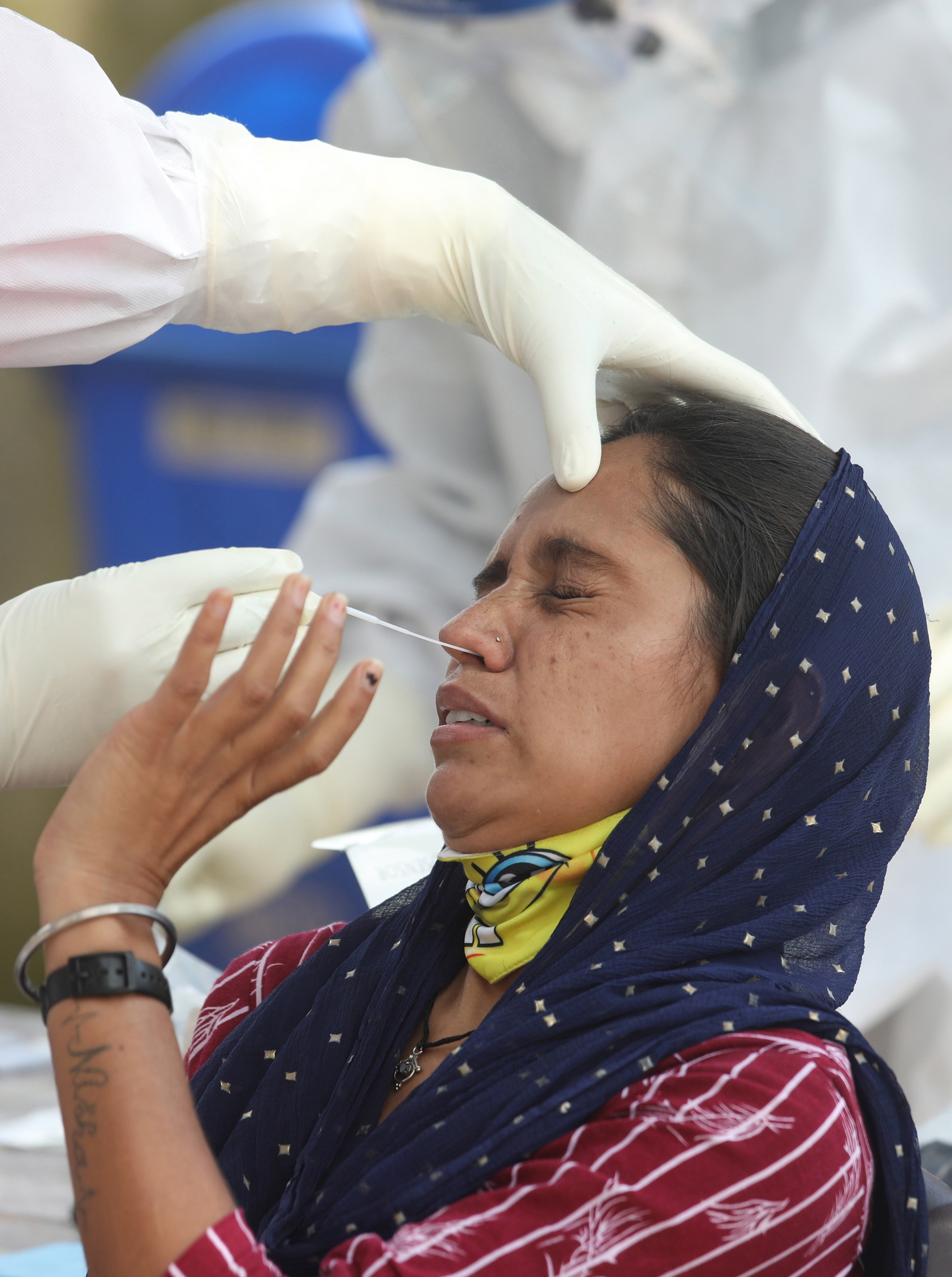 Una mujer reacciona cuando un médico toma muestras para la prueba rápida para detectar covid-19 en la India, que se convirtió en el segundo país con más contagiados por la pandemia. (Foto Prensa Libre: EFE)