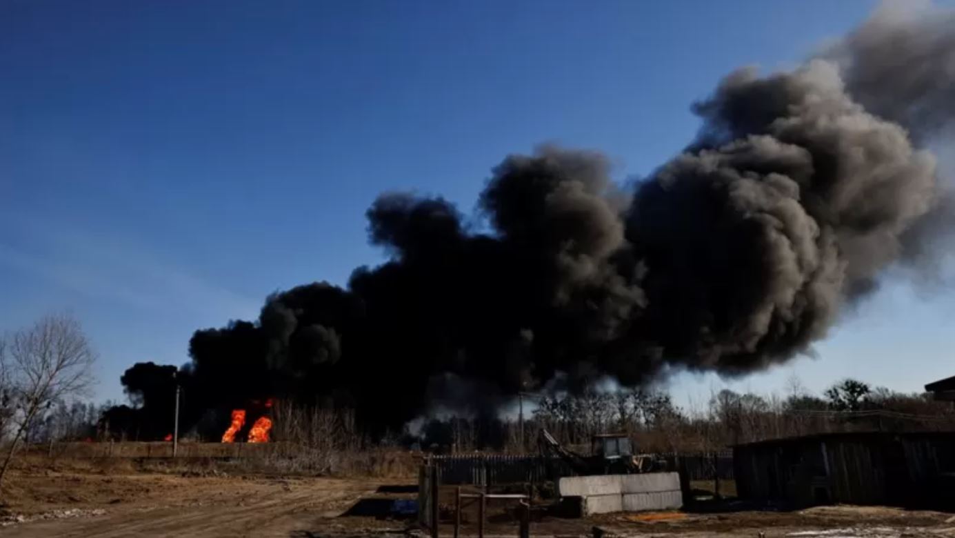 Una columna de humo se eleva desde tanques de combustible en llamas que, según los locales, fueron alcanzados por cinco cohetes en la base aérea de Vasylkiv, en las afueras de Kiev este 12 de marzo.

