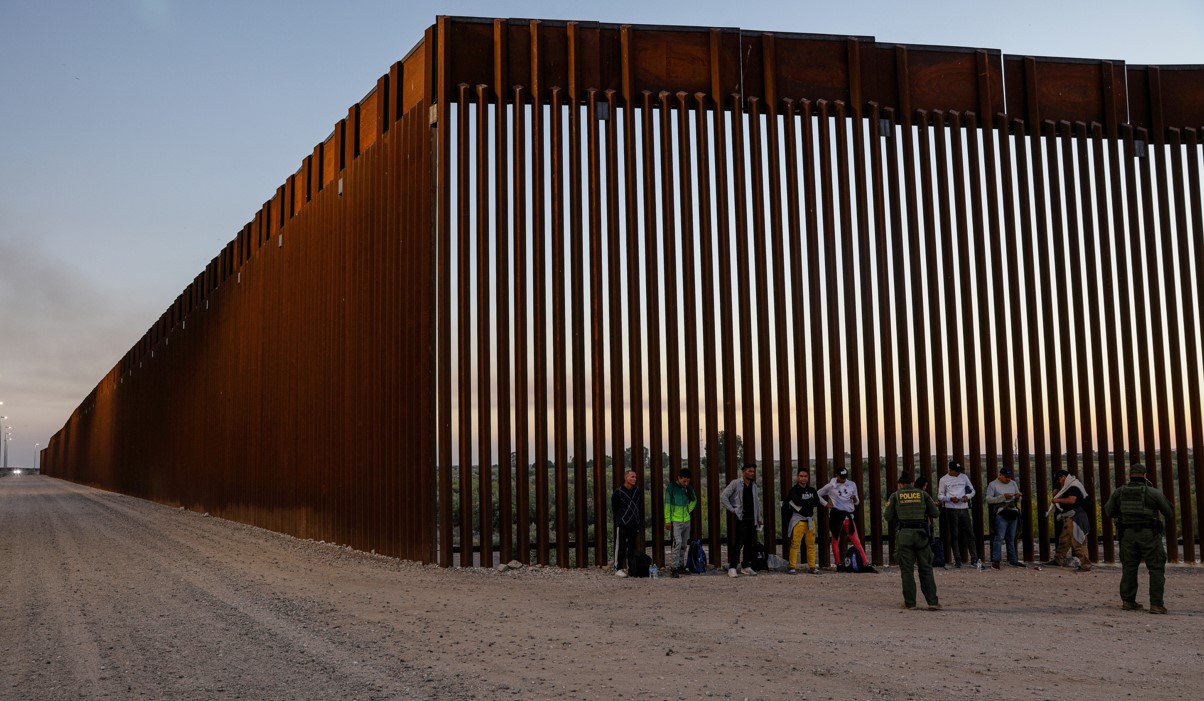 Un grupo de migrantes, a quienes se detuvo para procesamiento tras entregarse, en el muro fronterizo con México, en Yuma, Arizona, el 11 de mayo de 2023. (Adriana Zehbrauskas/The New York Times).