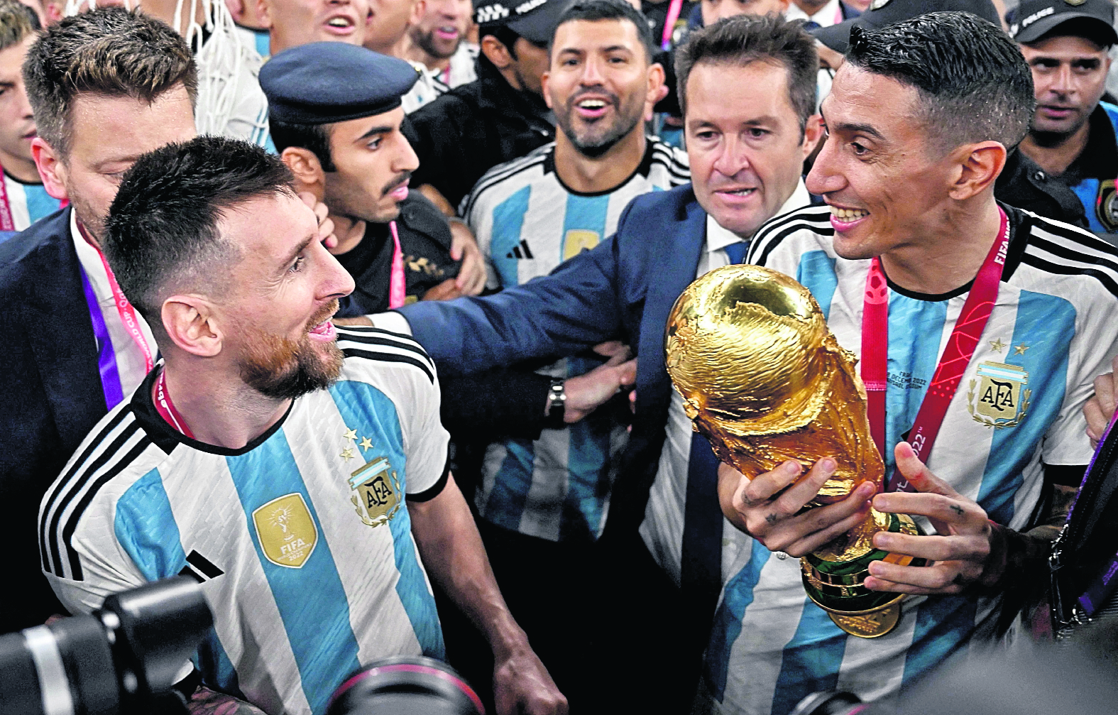 (FILES) Argentina's midfielder #11 Angel Di Maria (R) holds the FIFA World Cup Trophy as he speaks to Argentina's forward #10 Lionel Messi (L) following the trophy ceremony after Argentina won the Qatar 2022 World Cup final football match between Argentina and France at Lusail Stadium in Lusail, north of Doha on December 18, 2022. The American and world champion Angel Di Maria announced on November 23, 20223 that he will leave the Argentine football team after playing the 2024 Copa America in the United States. "With all the pain in my soul and feeling a lump in my throat, I say goodbye to the most beautiful thing that happened to me in my career", said "Fideo" Di Maria, 35, in a message published on the social network Instagram. (Photo by Anne-Christine POUJOULAT / AFP)
