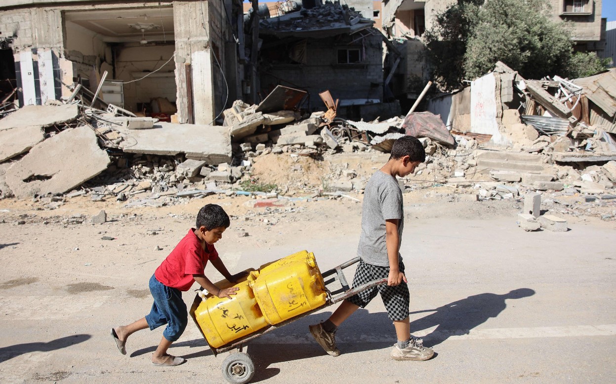 Niños transportan galones con agua en la ciudad de Gaza. Varios menores civiles murieron durante las operaciones de rescate de rehenes en  la Franja. (Foto Prensa Libre: AFP)