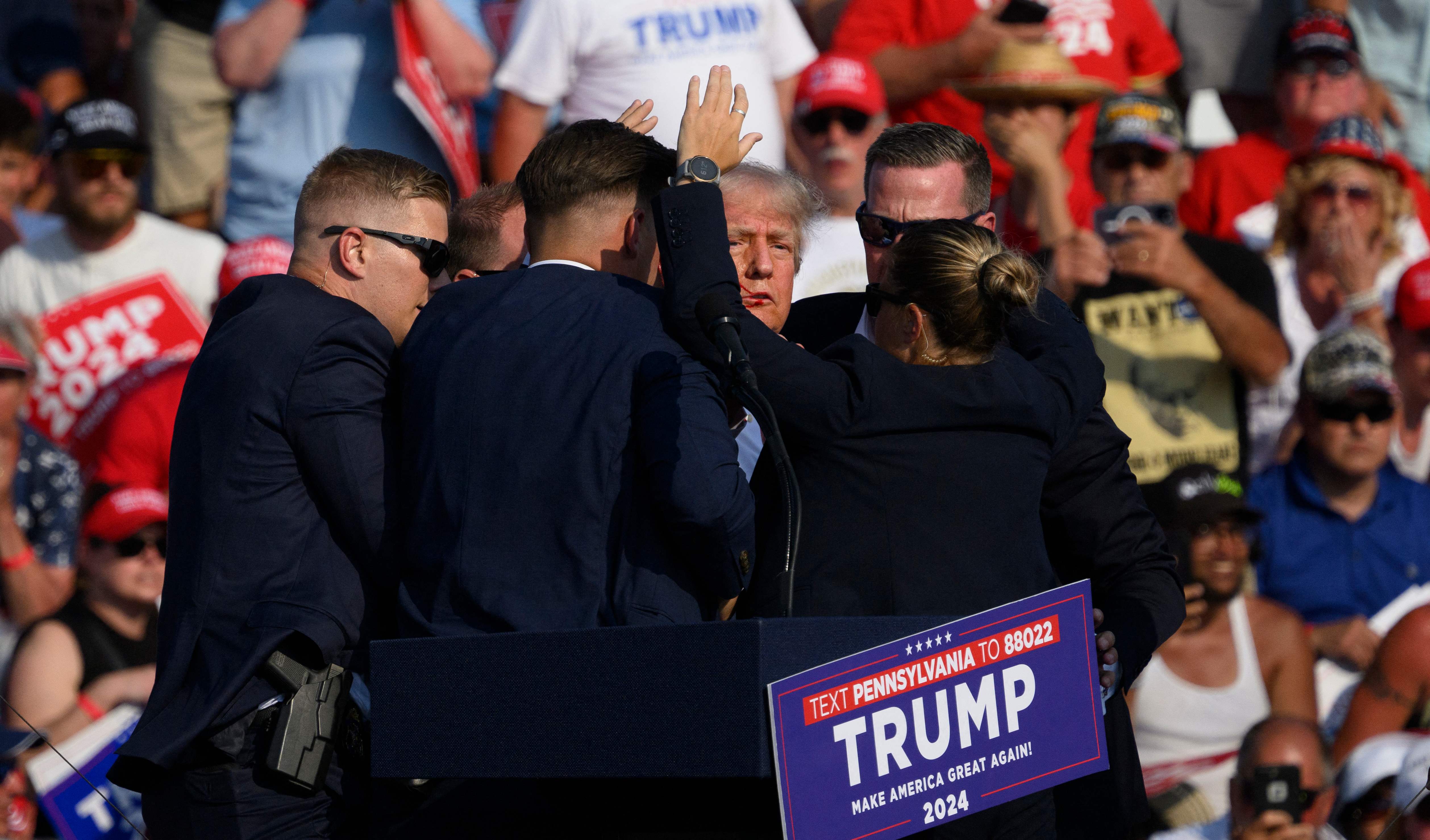 BUTLER, PENNSYLVANIA - JULY 13: Secret Service agents surround Republican presidential candidate former President Donald Trump onstage after he was injured at a rally on July 13, 2024 in Butler, Pennsylvania. According to Butler County District Attorney Richard Goldinger, the suspected gunman is dead after injuring former President Trump, killing one audience member and injuring at least one other.   Jeff Swensen/Getty Images/AFP (Photo by JEFF SWENSEN / GETTY IMAGES NORTH AMERICA / Getty Images via AFP)