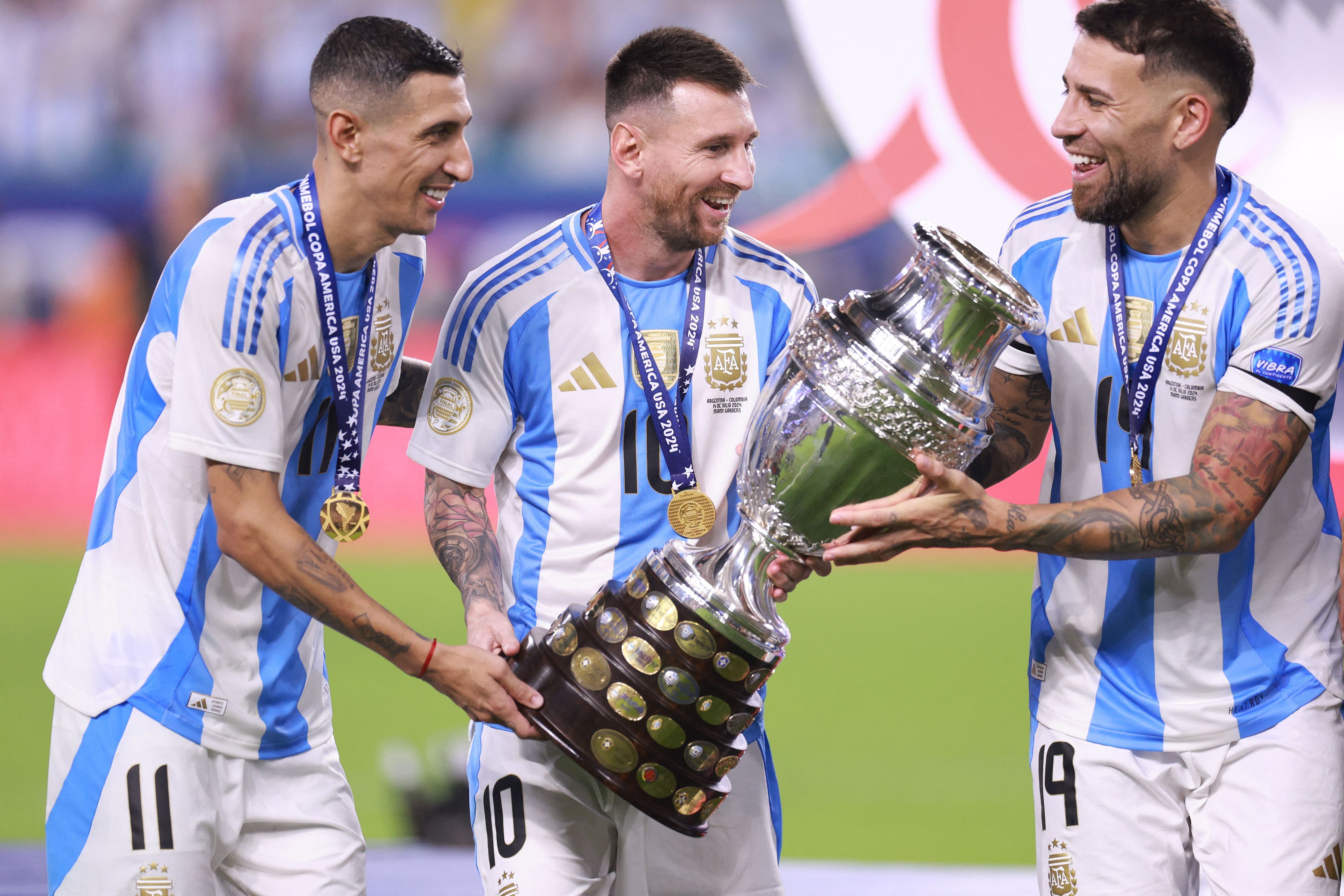 Angel Di María (izquierda), Nicolás Otamendi (derecha) y Lionel Messi (centro) a punto de levantar la Copa América.