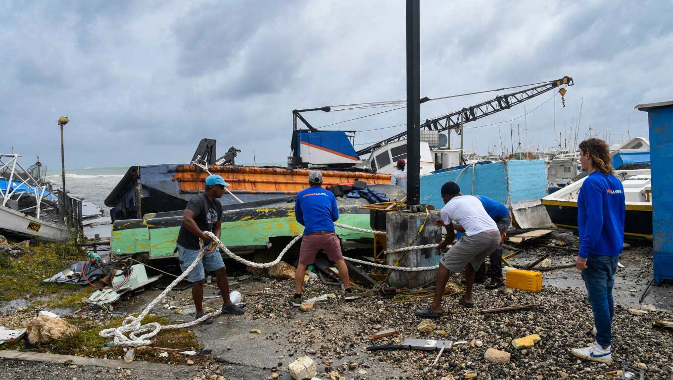 Pescadores de Bridgetown, Barbados, intentan rescatar un barco pesquero dañado tras el paso del huracán Beryl. (Foto Prensa Libre: Randy Brooks / AFP)