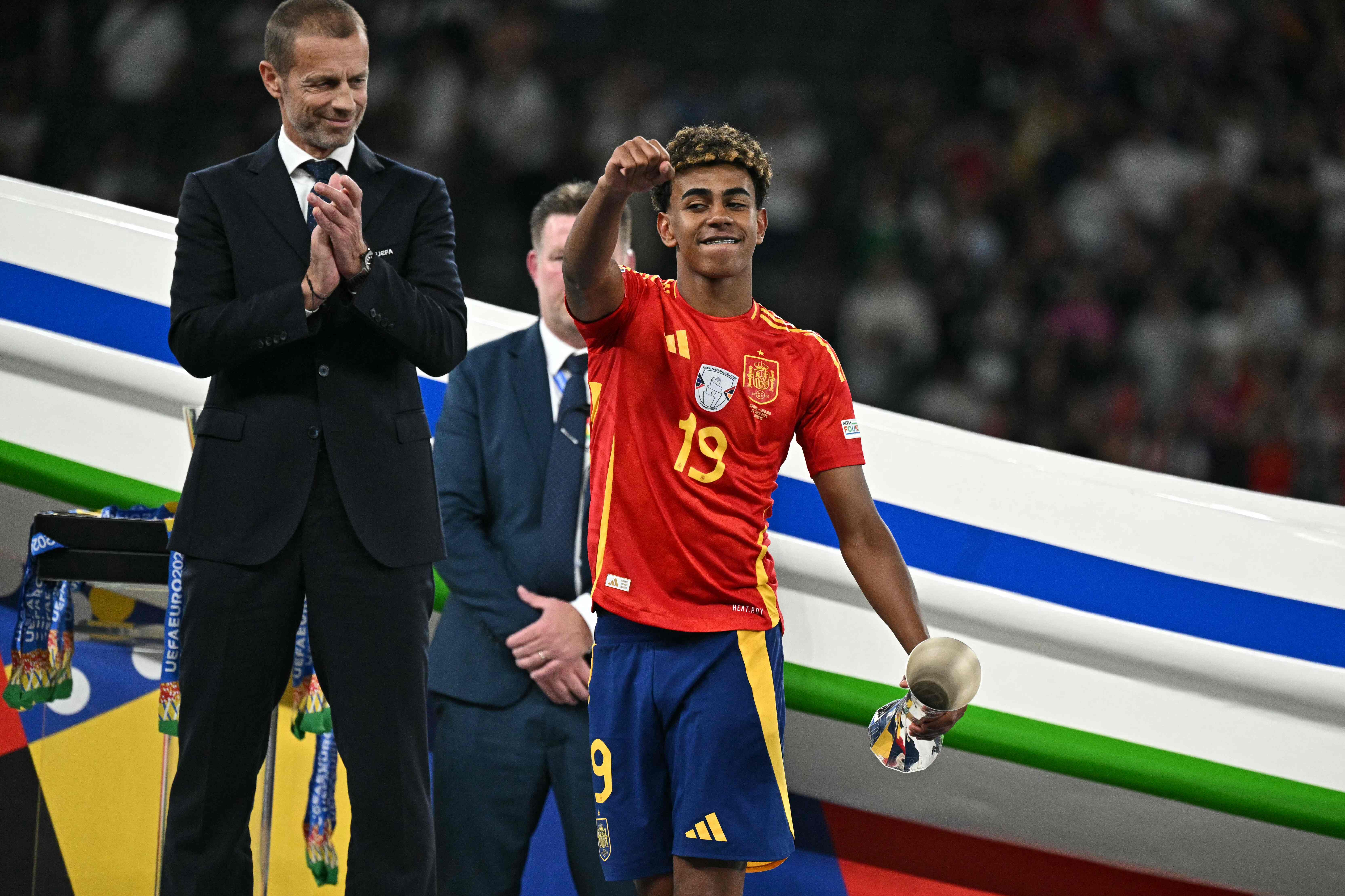 Spain's forward #19 Lamine Yamal celebrates with the Best Young player trophy next to UEFA President Aleksander Ceferin after winning the UEFA Euro 2024 final football match between Spain and England at the Olympiastadion in Berlin on July 14, 2024. (Photo by JAVIER SORIANO / AFP)