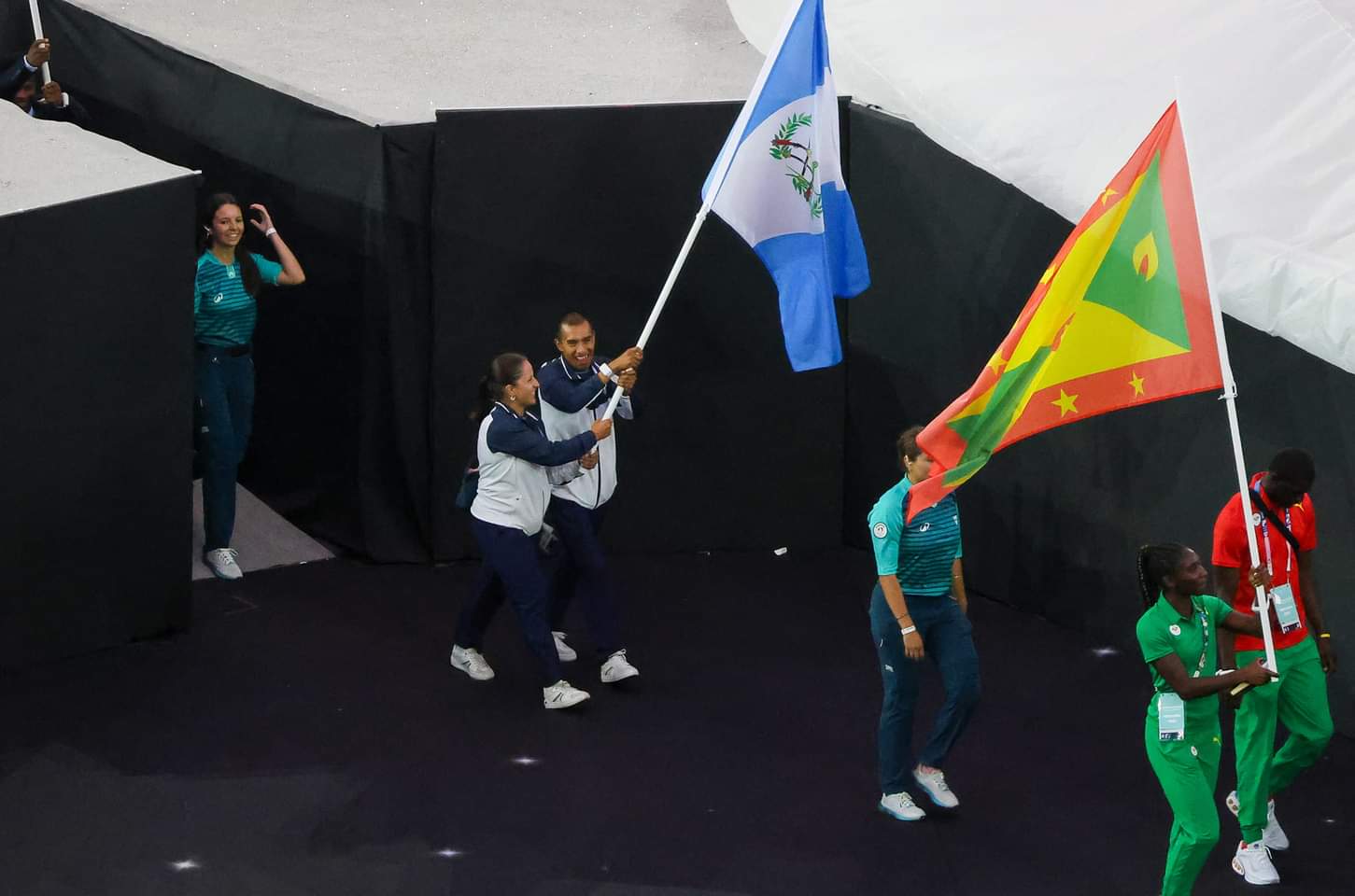 Adriana Ruano, medallista de oro para Guatemala, y el atleta Alberto González ondean con orgullo la bandera nacional durante la ceremonia de clausura de los Juegos Olímpicos de París 2024, celebrando un logro histórico para su país.'