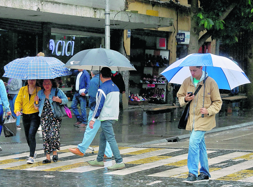 Personas se cubren de la lluvia que cae en el centro histÃ³rico de la ciudad. FotografÃ­a Esbin Garcia 31--10-23