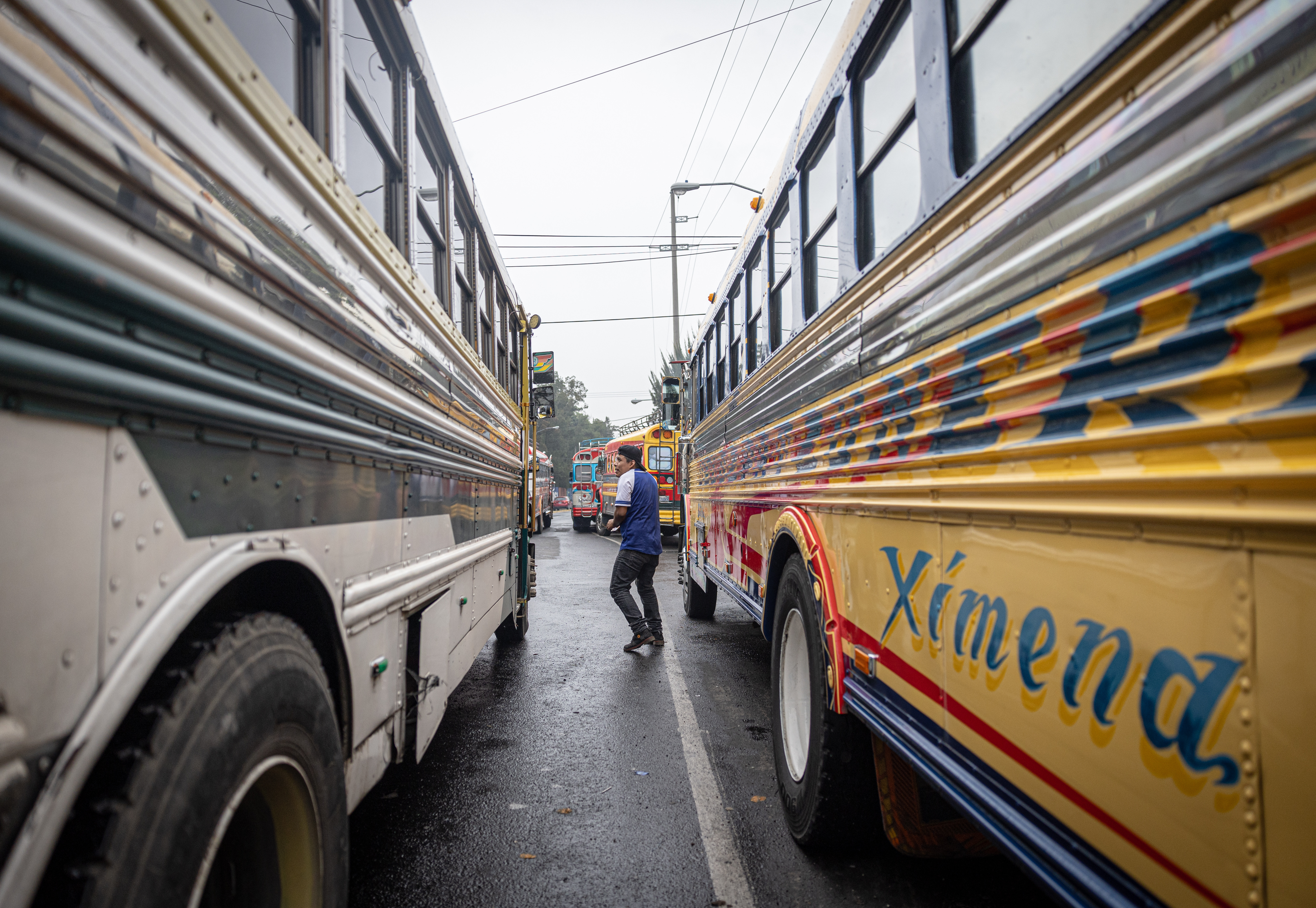 ACOMPAÑA CRÓNICA: GUATEMALA CENTROAMÉRICA EXTORSIONES. AME2696. CIUDAD DE GUATEMALA (GUATEMALA), 26/09/2024.- Un hombre camina entre dos autobuses extraurbanos este miércoles, en Ciudad de Guatemala (Guatemala). La profesión de conducir un taxi o un autobús en Guatemala y Honduras se ha convertido en un oficio de alto riesgo, viéndose los conductores muchas veces asediados entre el pago de las extorsiones o la muerte, con más de 5.000 choferes asesinados entre 2010 y 2024 en estos países. EFE/ Stringer