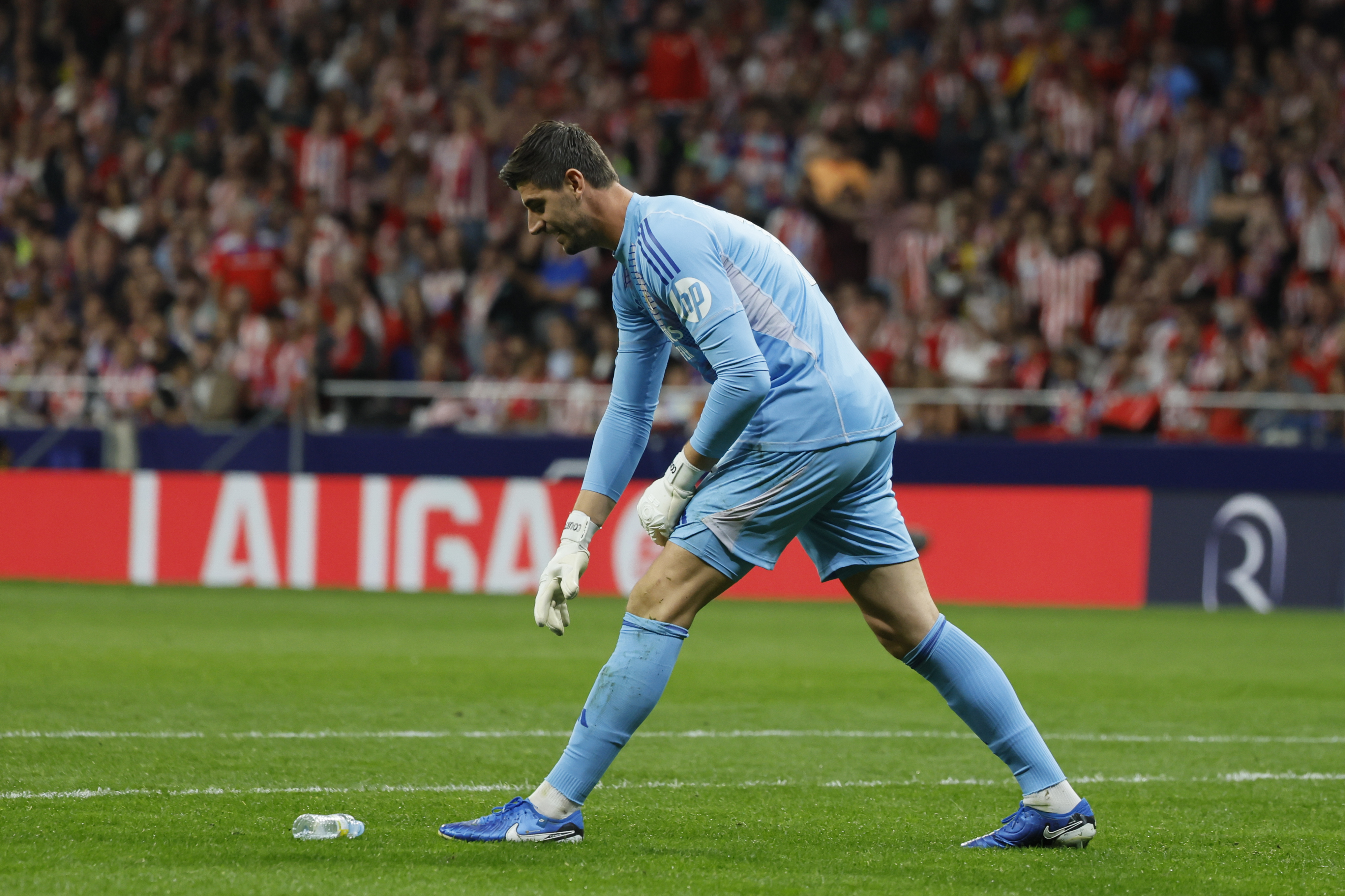 El portero del Real Madrid Thibaut Courtois retira un objeto lanzado desde la grada, durante el partido entre Atlético de Madrid y Real Madrid.