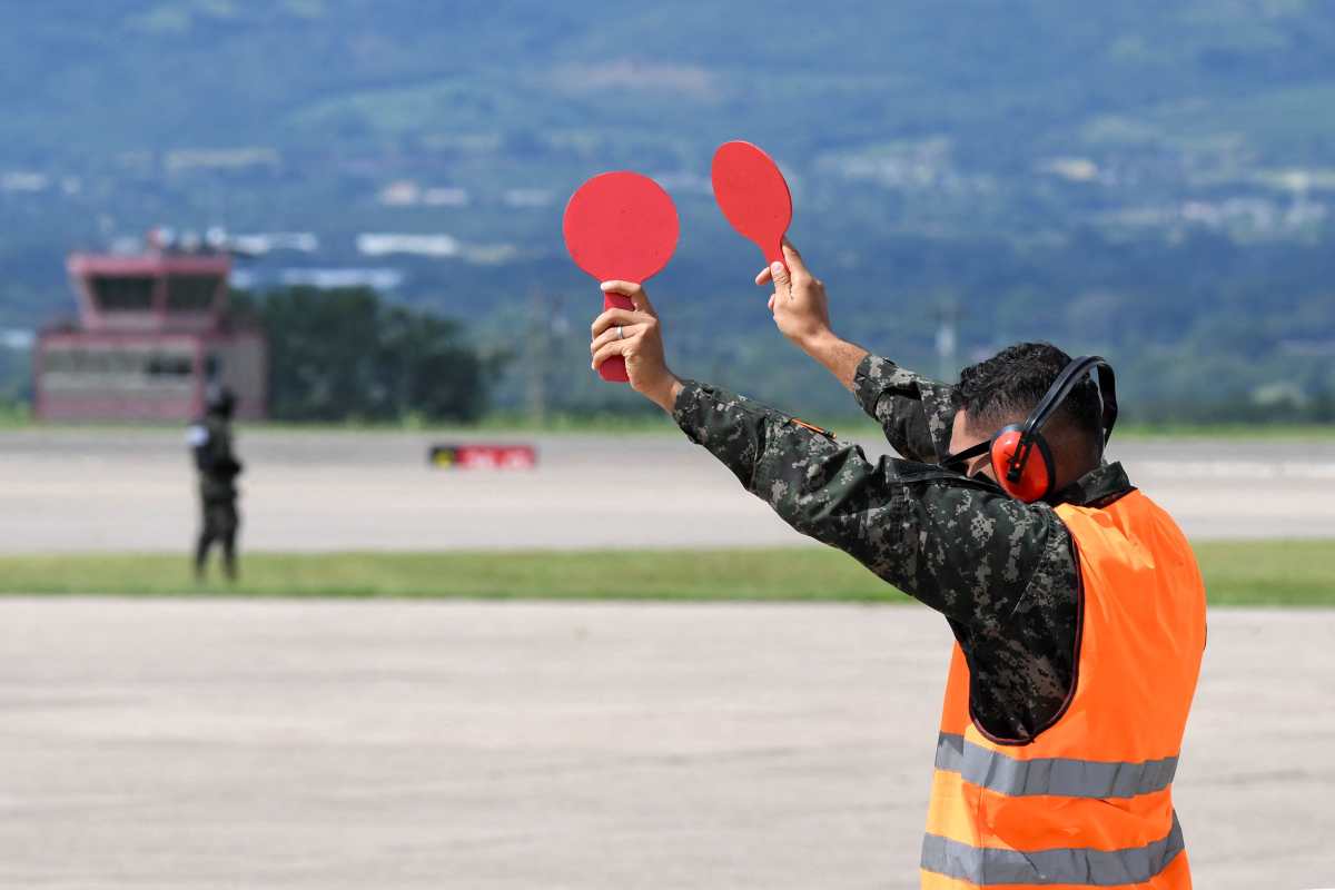 A military officer guides the pilots of the plane where Javier Marin Gonzales, better known as the "Fentanyl King," is being transported after being handed over to FBI and DEA agents for extradition at the Palmerola Air Base in Comayagua, 50 km north of Tegucigalpa, on October 23, 2024. Honduras handed over an alleged fentanyl trafficker to the United States on Wednesday, almost two months after canceling the extradition treaty between the two countries, police said. (Photo by Orlando SIERRA / AFP)