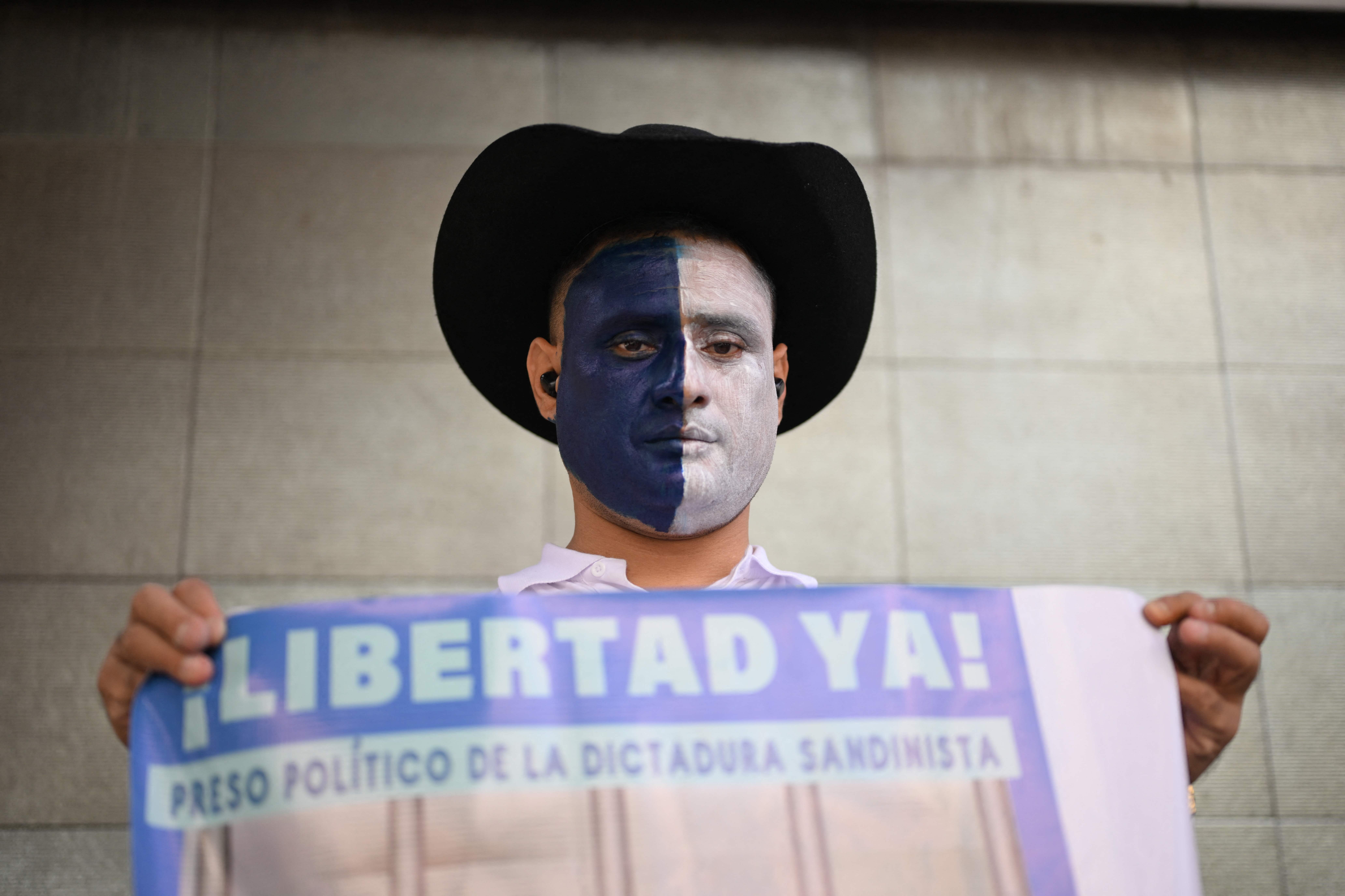 El expreso político nicaragüense Eduardo Rodríguez muestra una pancarta en la que pide la liberación de otros encarcelados por el régimen de Daniel Ortega. (Foto Prensa Libre: JOHAN ORDÓNEZ/AFP)