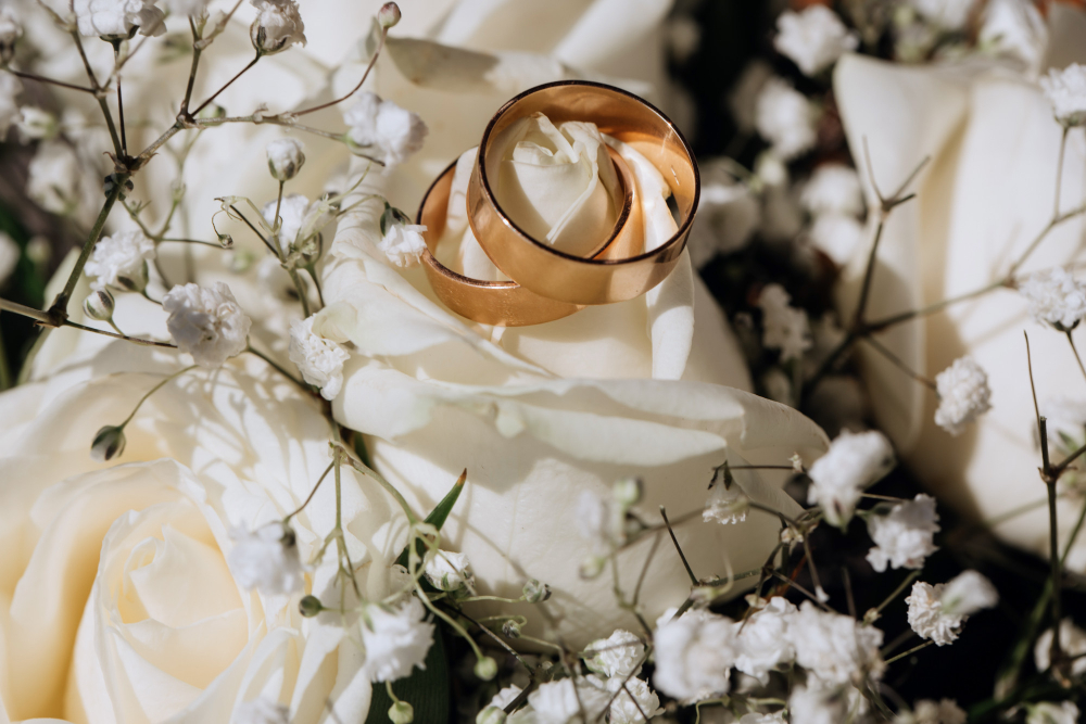 Dos anillos de boda sobre unas flores blancas.