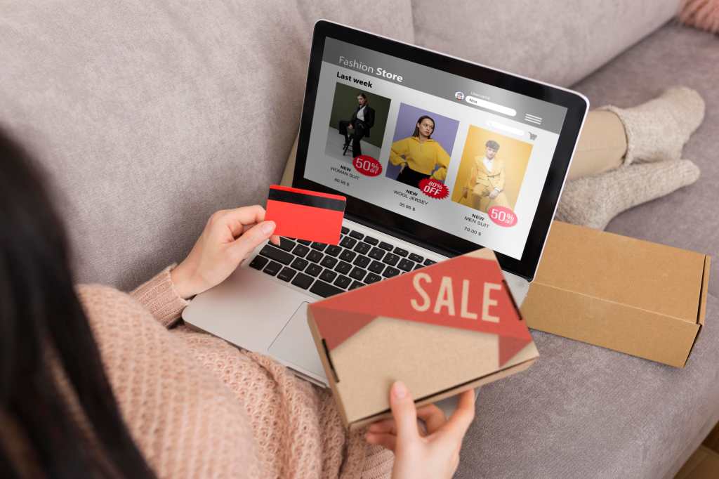 Una mujer sentada en un sofá con una computadora portátil en su regazo, realizando compras en línea.