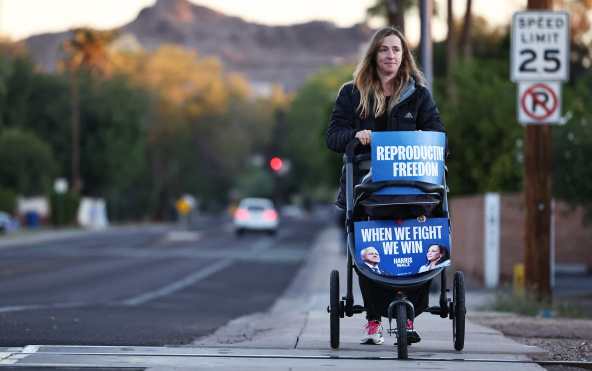 TEMPE, ARIZONA - NOVEMBER 05: Mother Julie Bufkin pushes her daughter Alice's stroller, adorned with 'Reproductive Freedom' and 'When We Fight We Win' signs, on November 05, 2024 in Tempe, Arizona. Passage of Proposition 139 in Arizona would codify the fundamental right to an abortion in the swing state of Arizona. Americans cast their ballots today in the presidential race between Republican nominee former President Donald Trump and Democratic nominee Vice President Kamala Harris, as well as multiple state elections that will determine the balance of power in Congress.   Mario Tama/Getty Images/AFP (Photo by MARIO TAMA / GETTY IMAGES NORTH AMERICA / Getty Images via AFP)