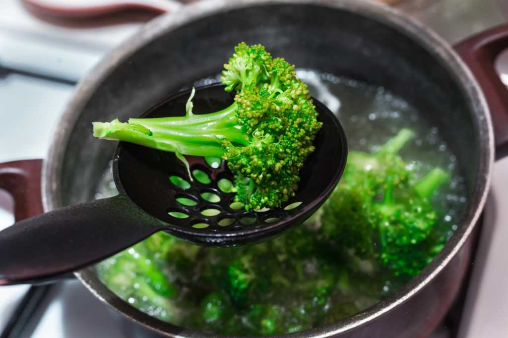 Hervir brócoli crudo en agua en una sartén metálica hirviendo. Cocina de verduras verdes