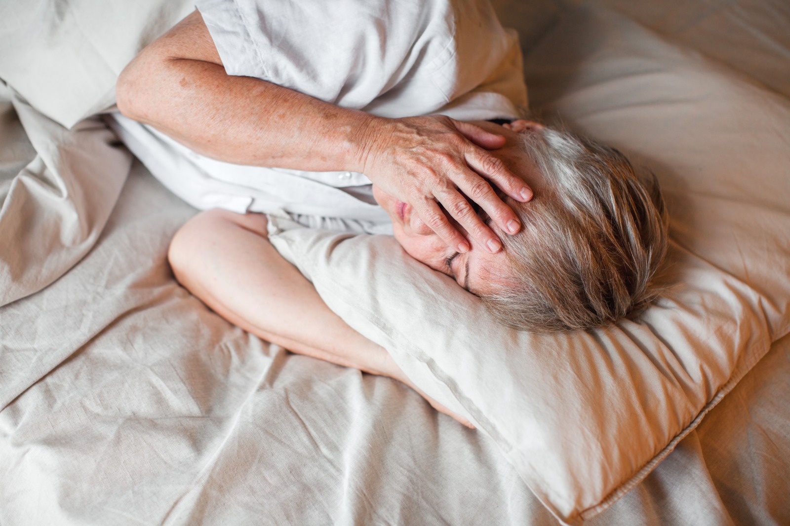 Mujer sin dormir de mediana edad con los ojos abiertos sobre una almohada suave cerca, con insomnio, falta de sueño, triste anciana acostada en la cama por la mañana, pensando, despertar temprano