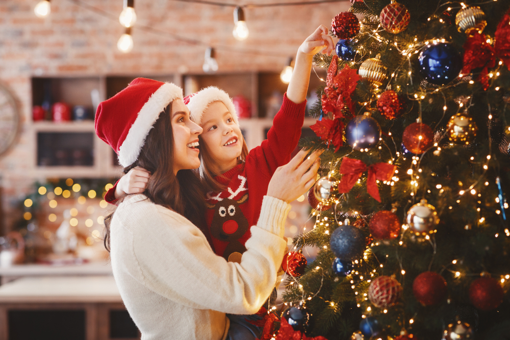 Mamá e hija decorando el árbol de navidad.