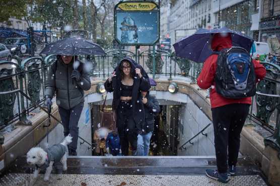 A commuter exits Colonel Fabien Metro station in heavy snowfall as Paris is placed under the second highest weather warning by the French national weather service for snow, in central Paris on November 21, 2024. Snow all the way to the plains, temperatures worthy of January: the first flakes of storm Caetano fell in France on November 21, where 54 departments are on 'orange alert' for snow, ice and wind. (Photo by Kiran RIDLEY / AFP)