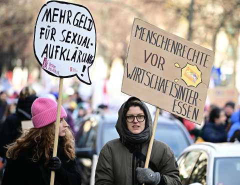 People carry banners reading "More money for sexual education" (L) and "Human rights before economic interests" during a protest under the motto "Uncuttable" against cuts in social work and youth welfare in the upcoming budget of Berlins senate on November 21, 2024 in Berlin.  (Photo by Tobias SCHWARZ / AFP)