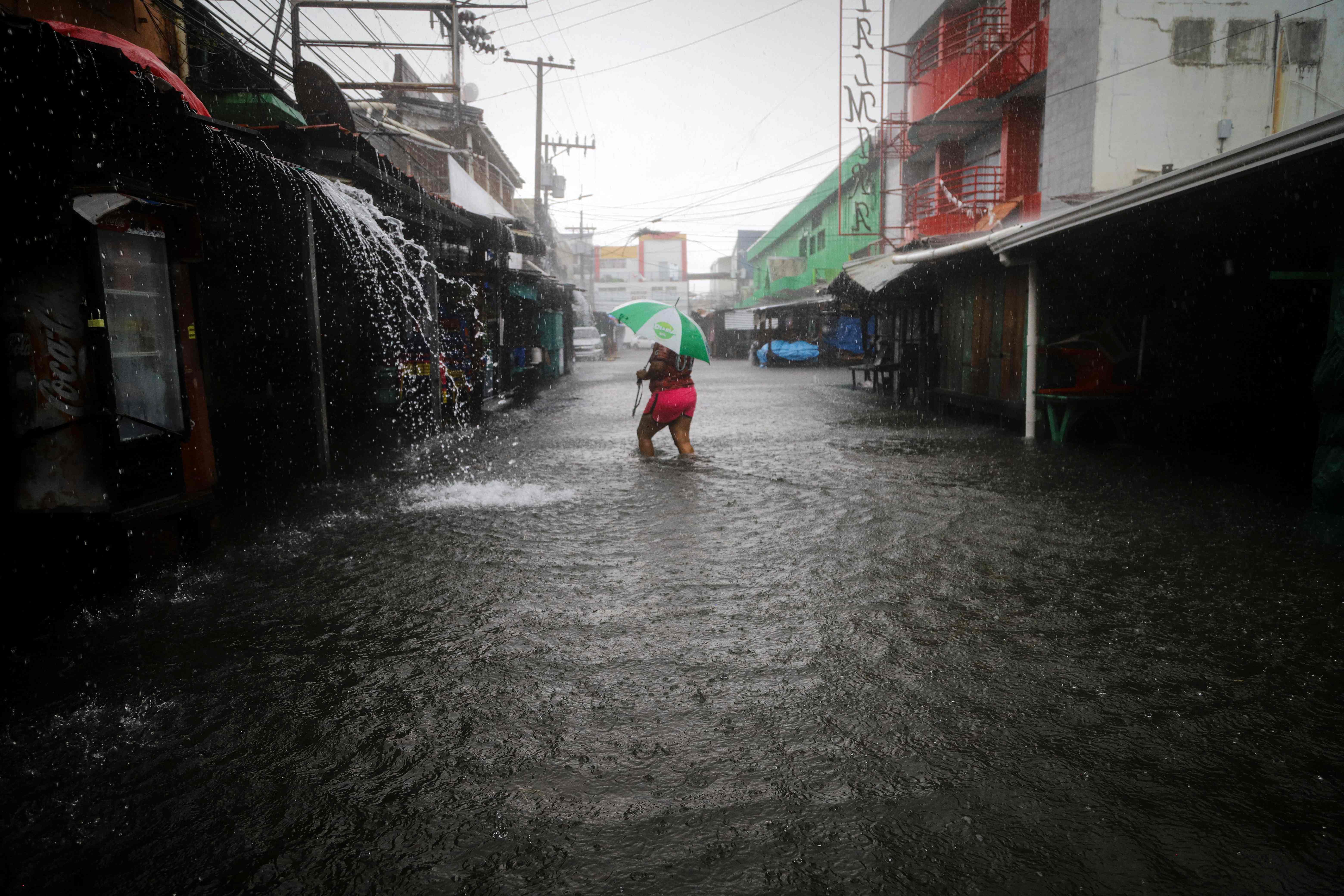 TOPSHOT - A woman walks along a flooded street during the passage of tropical storm Sara in La Ceiba, Honduras, on November 15, 2024. Honduras' President Xiomara Castro said emergency services had been activated to deal with "damage already caused by the rains," warning that Sara's impacts "could become a catastrophic event." (Photo by ESAU OCAMPO / AFP)