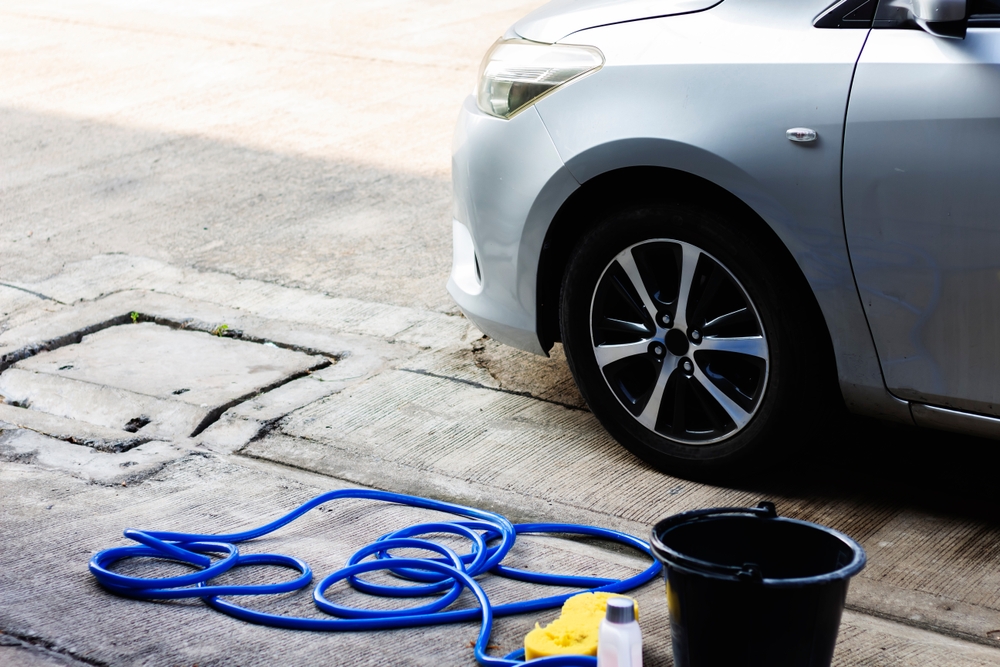 Equipamiento: manguera, líquido para lavar coches y cubo de agua para prepararse para lavar coches delante de la casa.