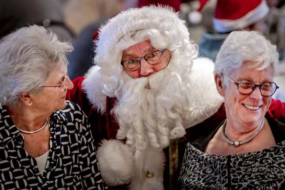 Apeldoorn (Netherlands), 12/12/2024.- A man dressed as Santa poses with two elderly during a Christmas high tea hosted by the National Elderly Fund at a Van der Valk Hotel in Apeldoorn, The Netherlands, 12 December 2024, organized to bring together over-65s and youth against loneliness around the holidays. (Países Bajos; Holanda) EFE/EPA/RAMON VAN FLYMEN