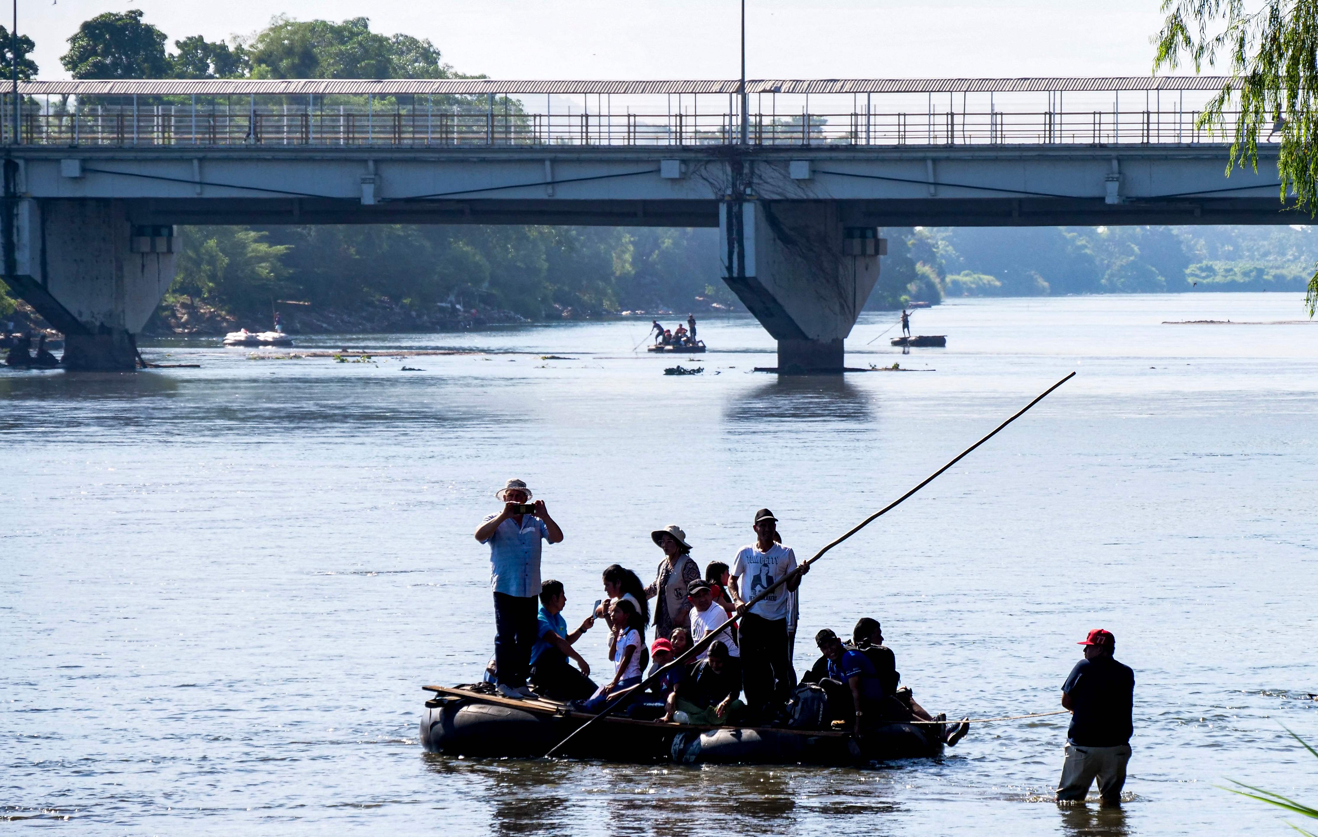 Migrants and members of the Casa del Migrante Sin Fronteras (House of Migrants Without Borders) cross the Suchiate River, the western border between Guatemala and Mexico, in Tecun Uman, Guatemala, on December 5, 2024. Casa del Migrante Sin Fronteras organized an event with the aim of raising awareness among the population about illegal migration. (Photo by STRINGER / AFP)